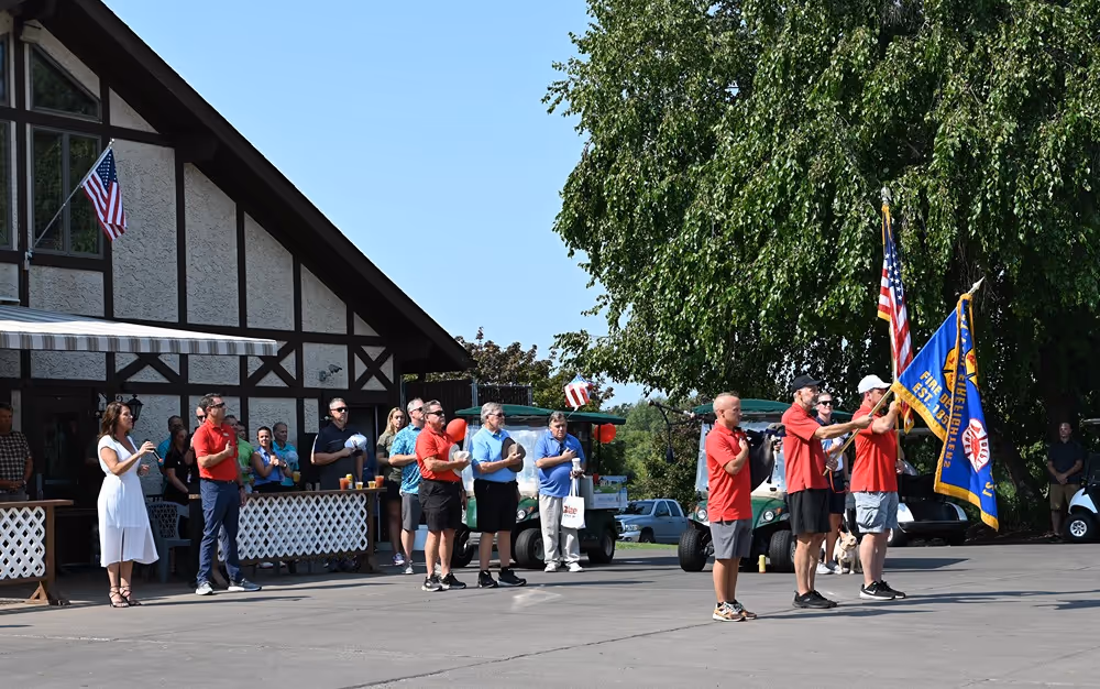 Saint Paul Firefighters Local 21 honor guard carrying flags during a ceremony as community members look on.