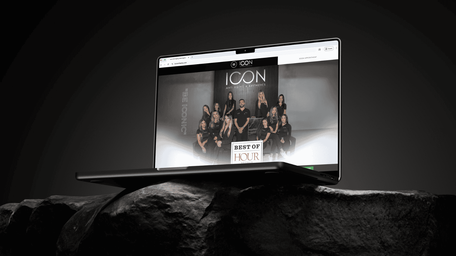 A Mac Book laptop sitting on a rock with a client, Icon Anti-Aging & Aesthetics in Birmingham, MI, on the screen.