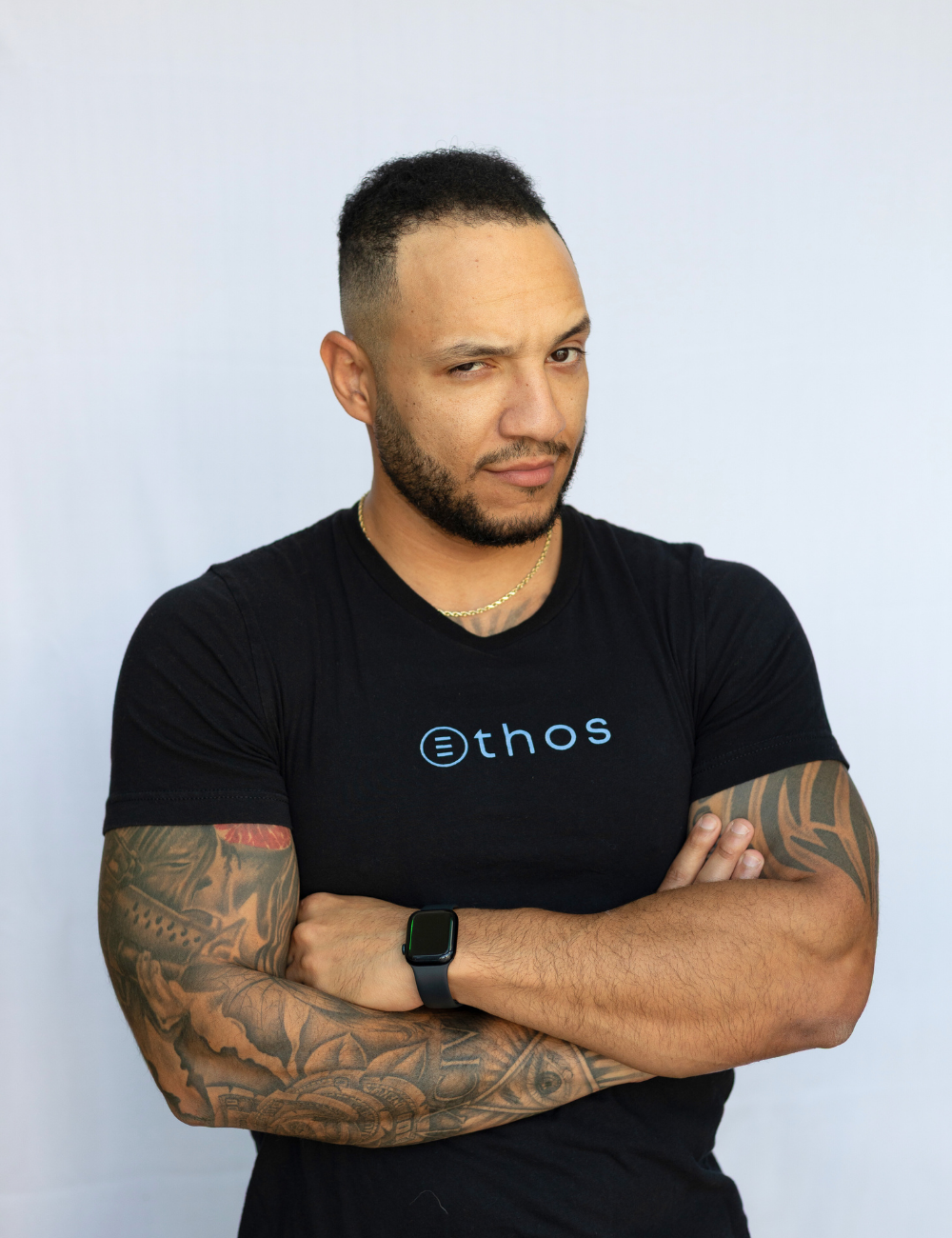 A man with arms crossed raising one eyebrow at the camera.