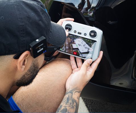 A man flying a drone looking at the drone controller.