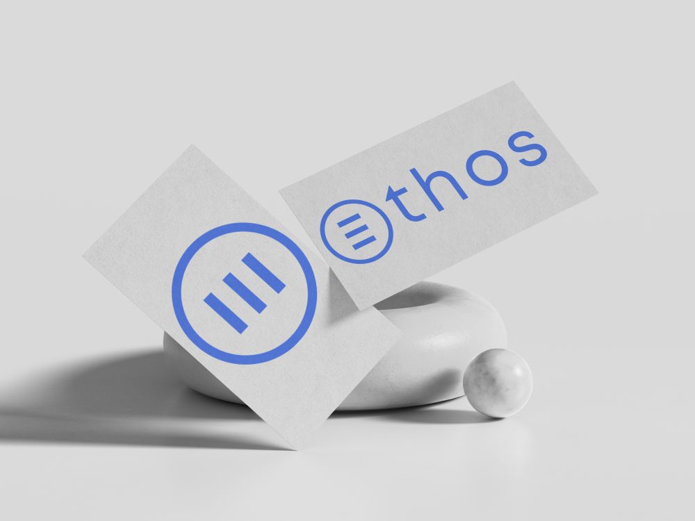 Two white business cards that have The Ethos Team logo on it.