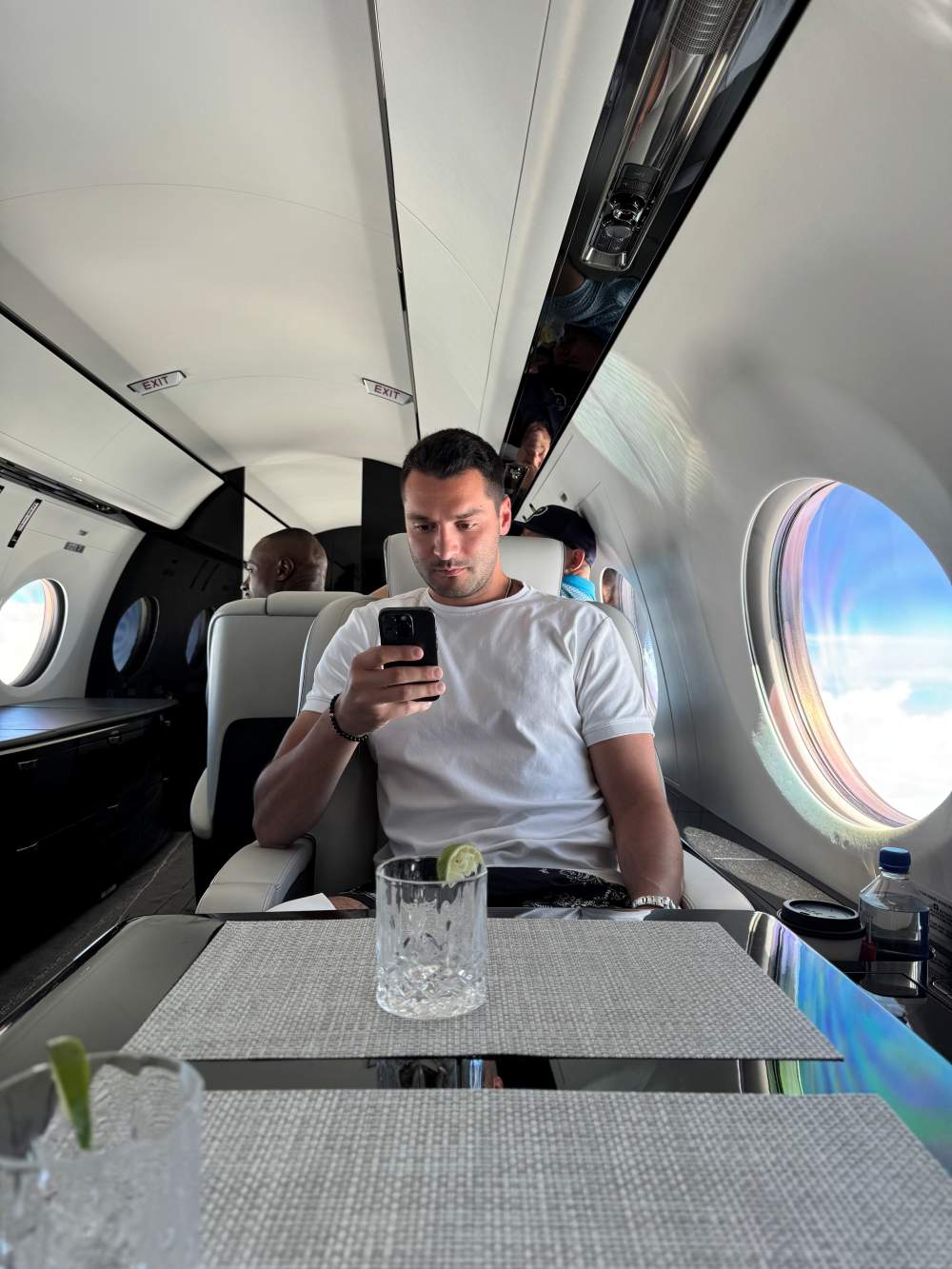 A man sitting on a private jet scrolling on his phone.