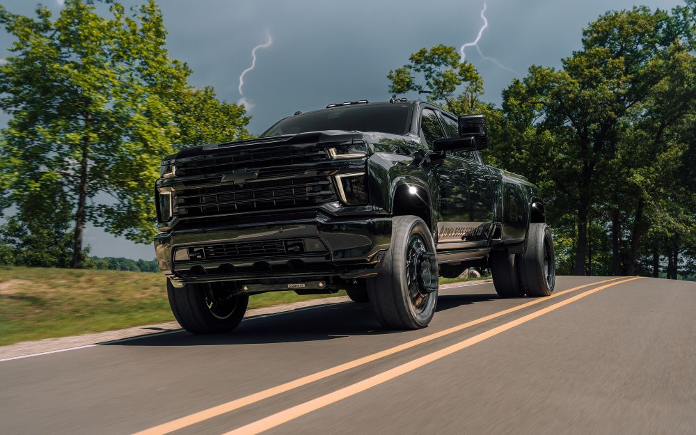A black Ram truck driving with lighting bolts behind it.