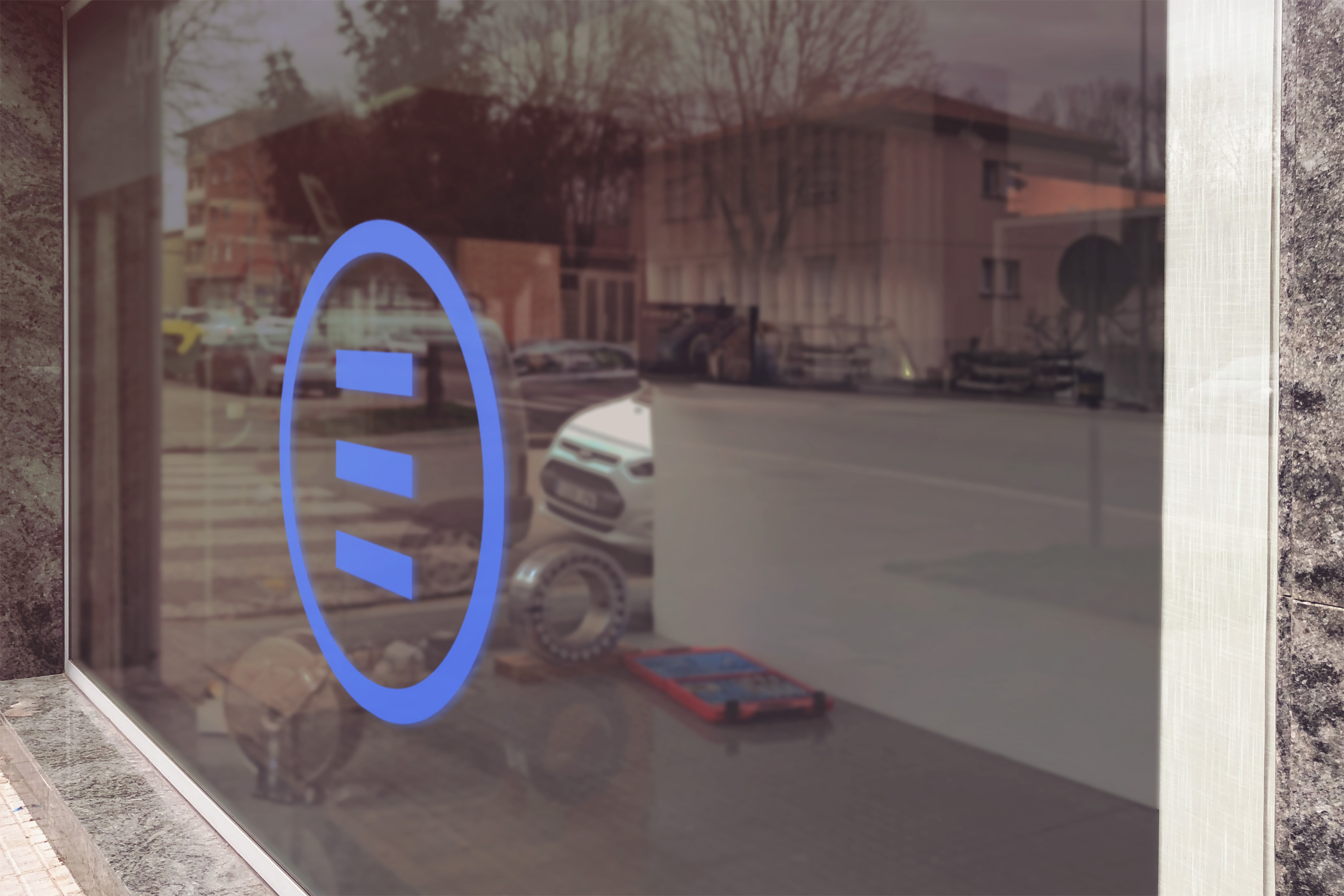 Blue logo on glass window reflecting automotive workshop interior