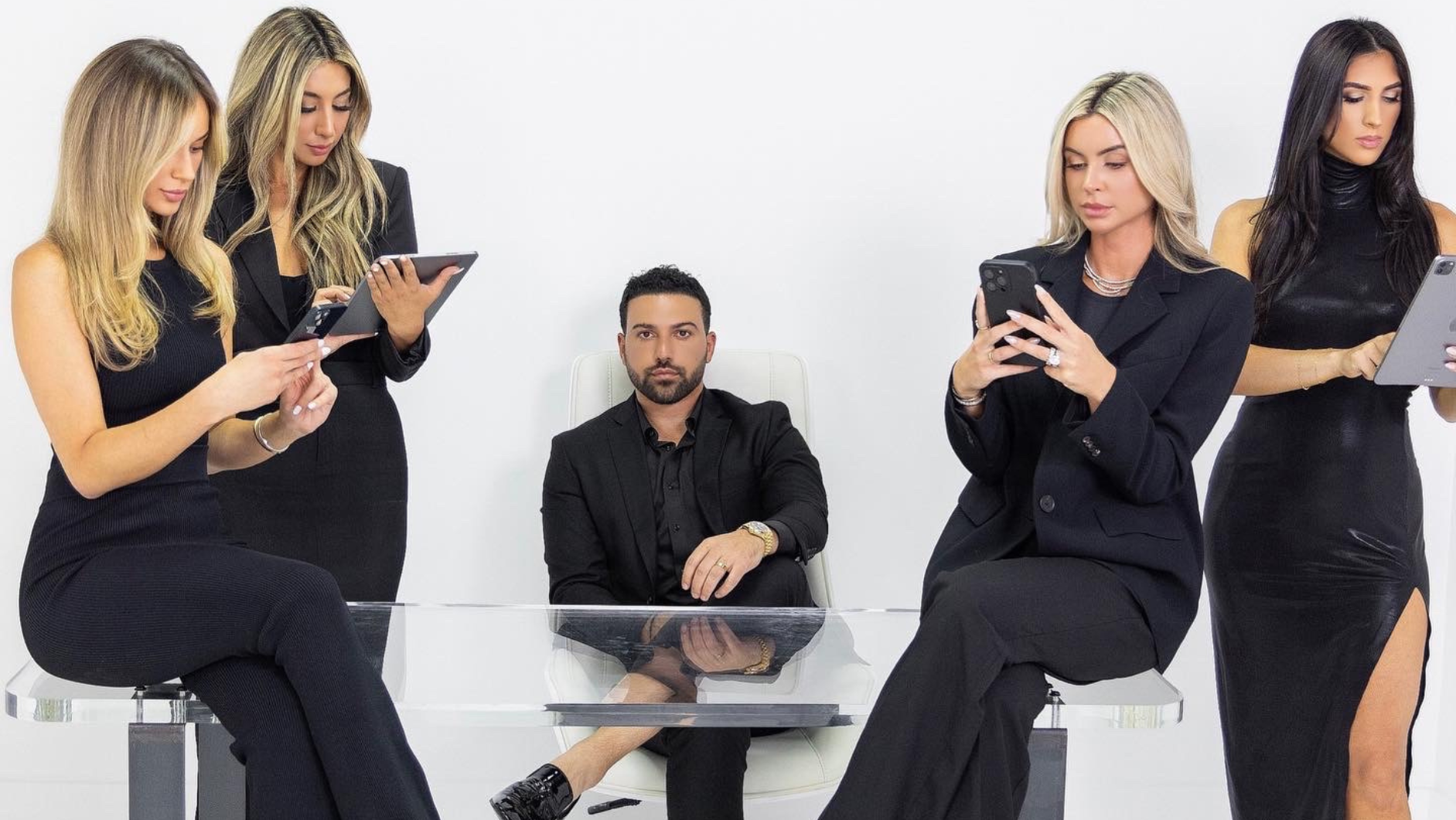 Business professionals in black attire using mobile devices around a clear table