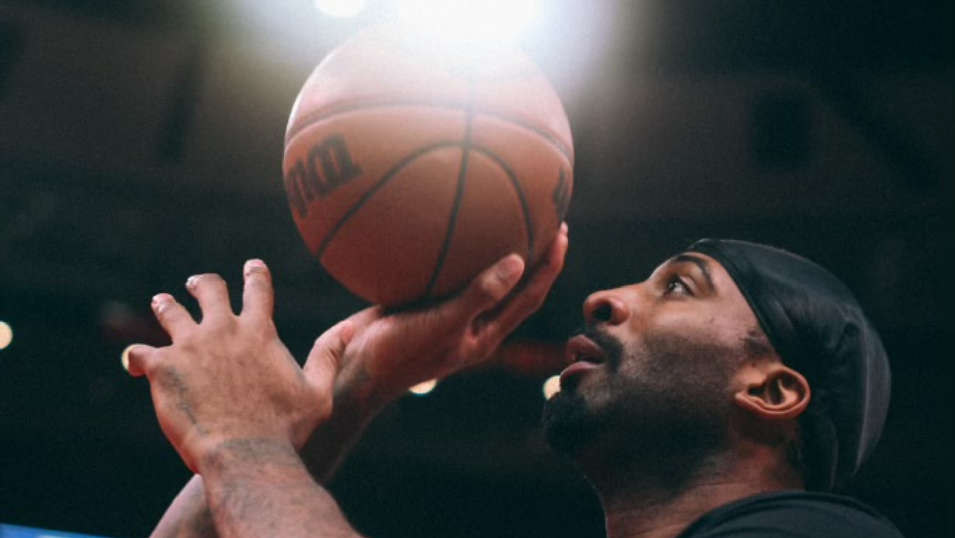Basketball player shooting with intense focus under bright arena lights