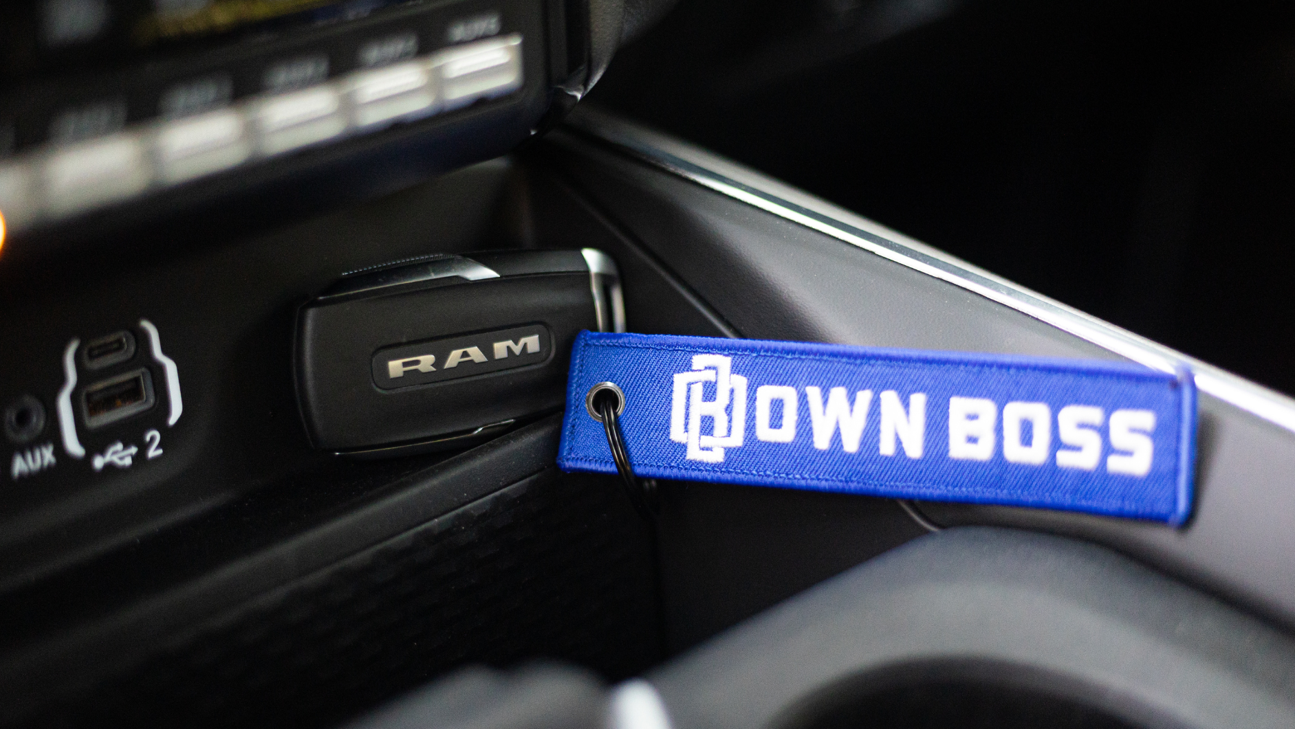 Blue "Own Boss" keychain hanging near RAM logo in vehicle interior