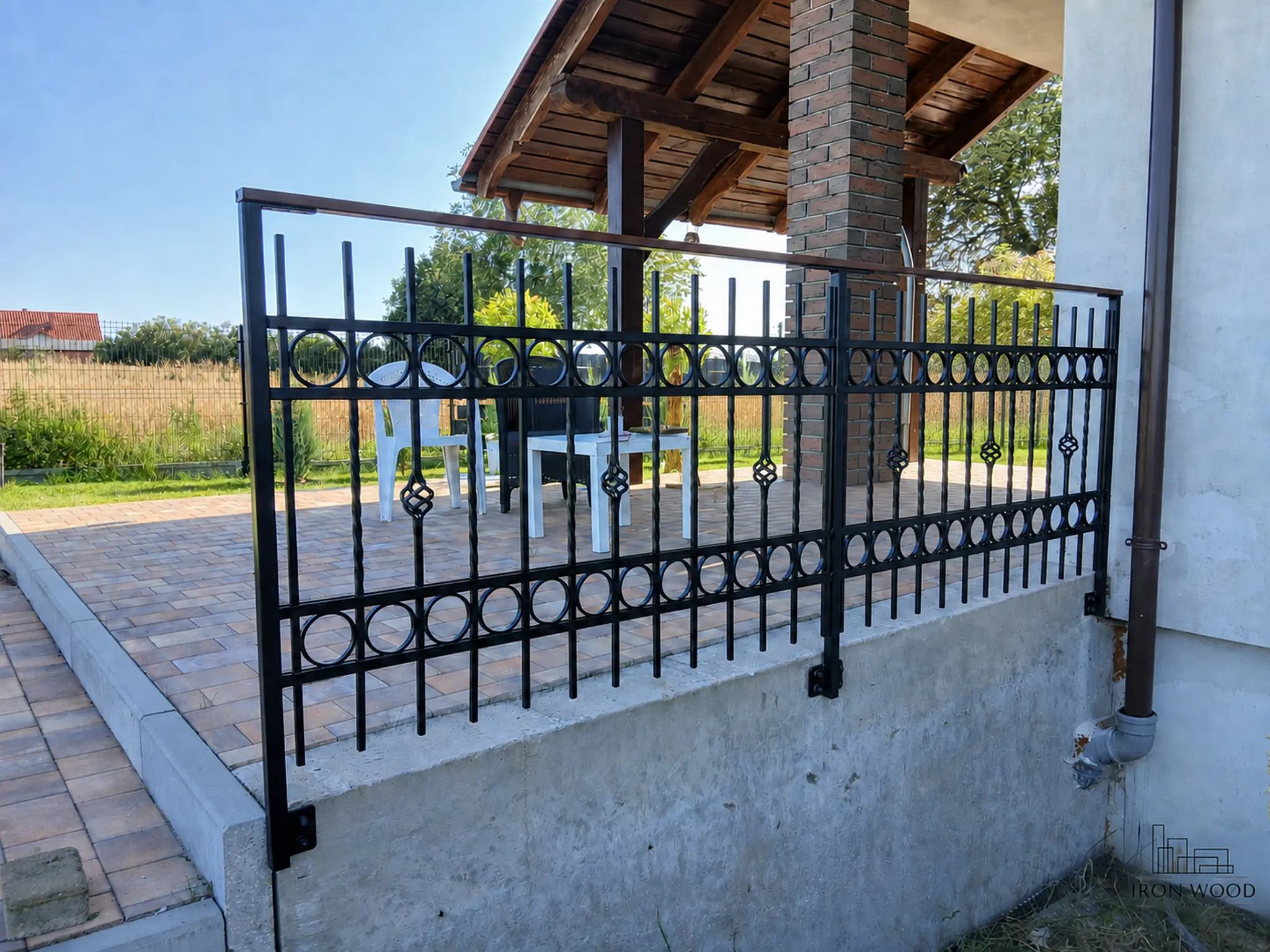 Nowoczesne schody z drewnianymi stopniami i czarną metalową balustradą w minimalistycznym wnętrzu z betonową ścianą i dużymi oknami.