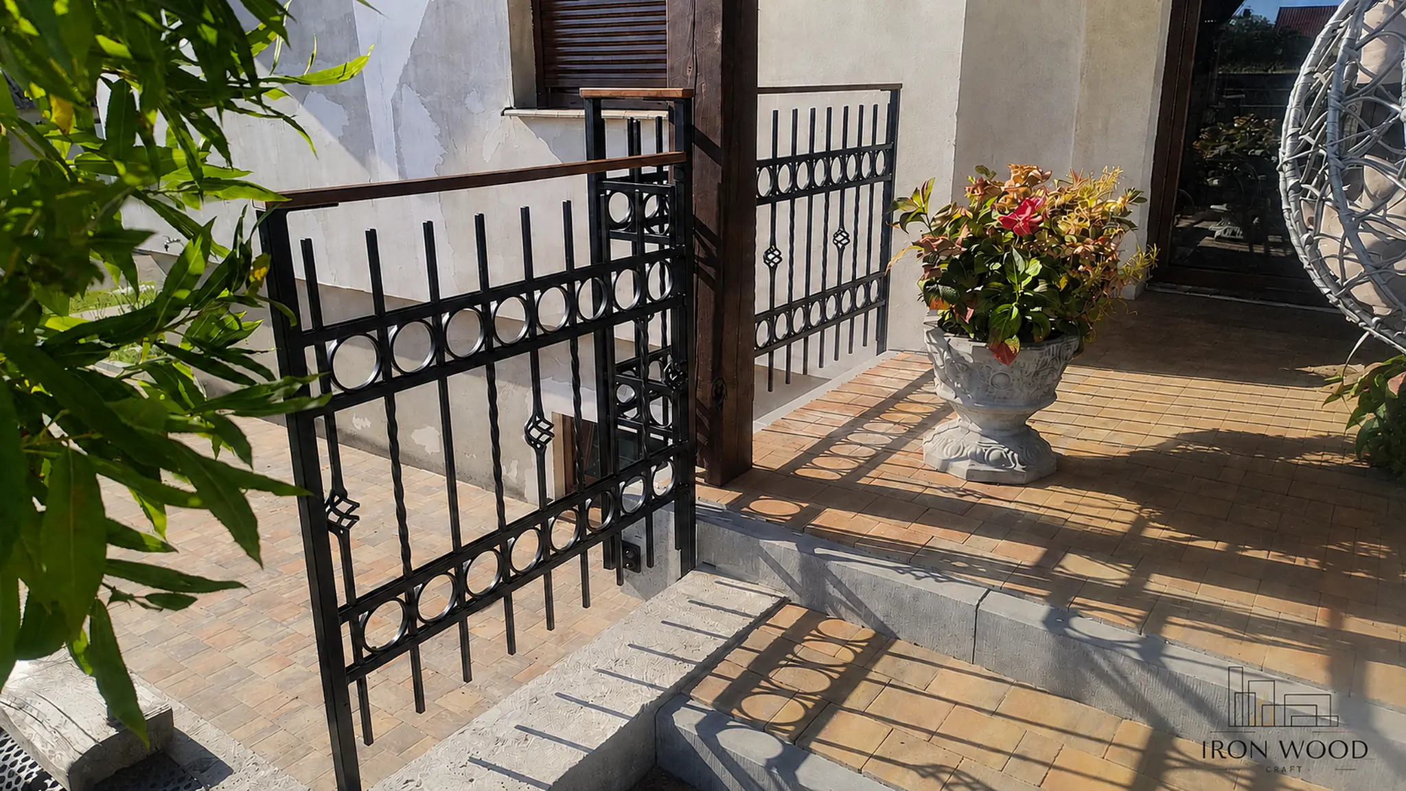 Nowoczesne schody z drewnianymi stopniami i czarną metalową balustradą w minimalistycznym wnętrzu z betonową ścianą i dużymi oknami.