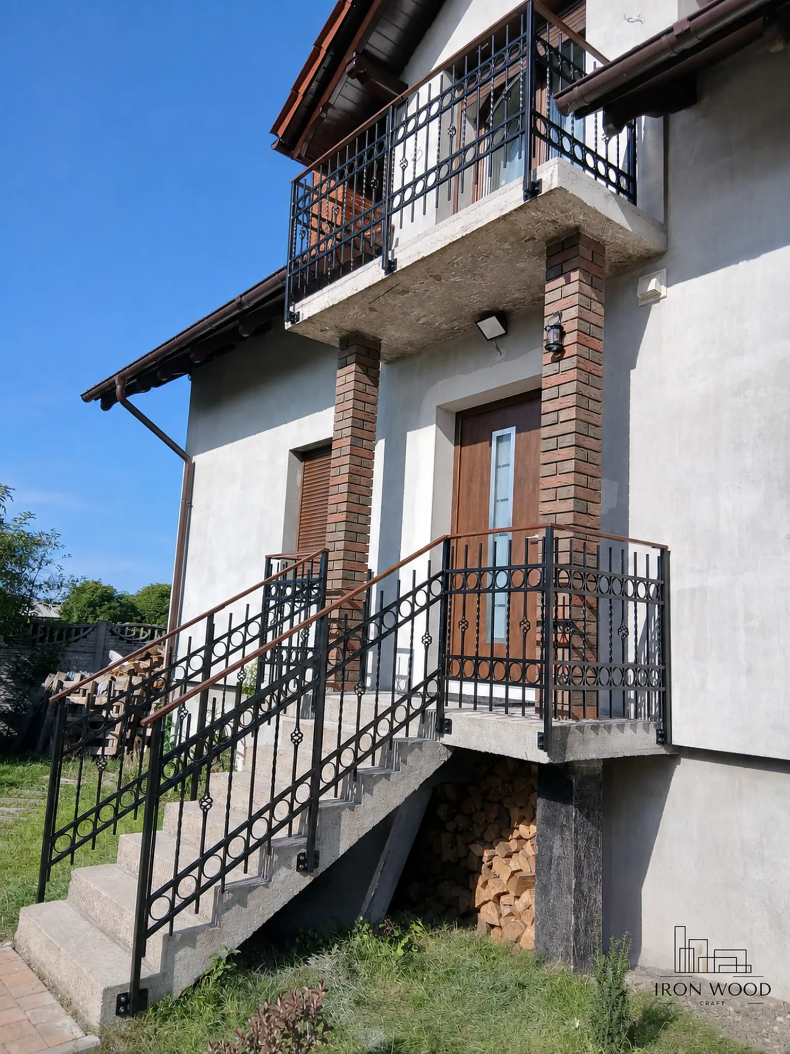 Nowoczesne schody z drewnianymi stopniami i czarną metalową balustradą w minimalistycznym wnętrzu z betonową ścianą i dużymi oknami.