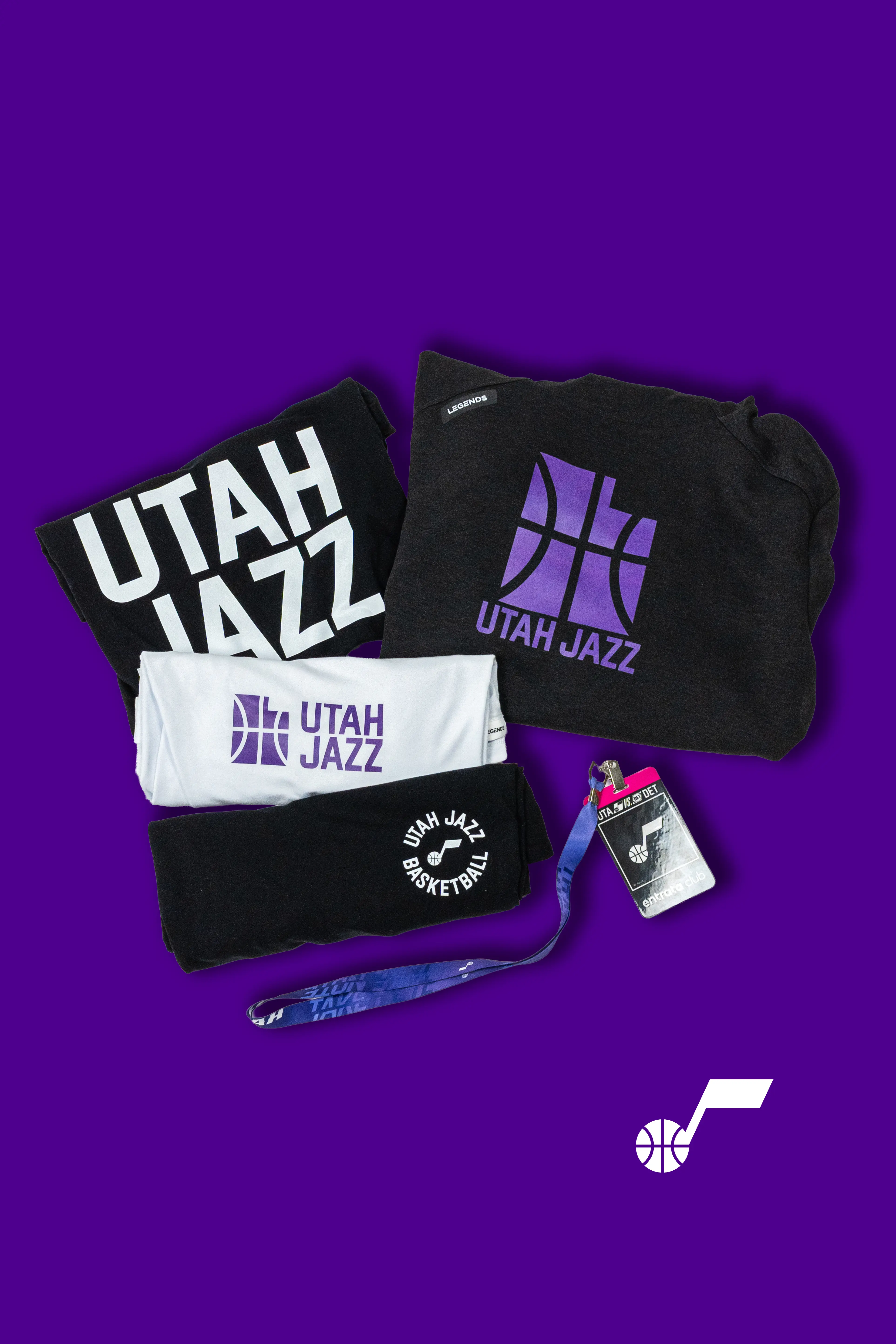 A flaylay of purple, black, and white Utah Jazz merch, including an ID card, tshirts, and a sweatshirt