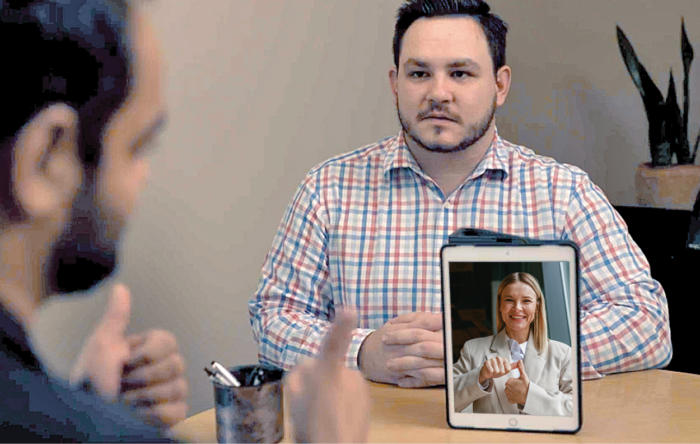 A Fidelity branch employee, a Fidelity customer communicating in ASL, and a Video Relay Interpreter facilitating communication using American Sign Language.