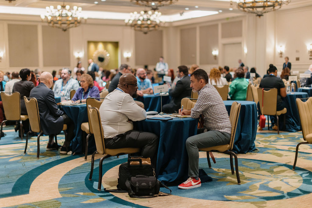 Conference attendees participate in structured networking conversations at round tables during a business matchmaking session.