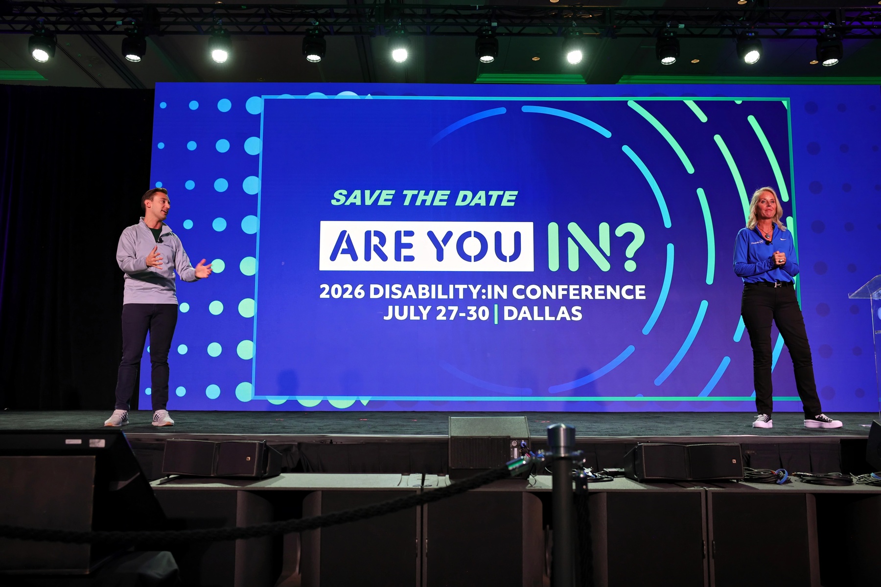 Presenters on the main stage announce the 2026 Disability:IN Global Conference in Dallas during a general session.