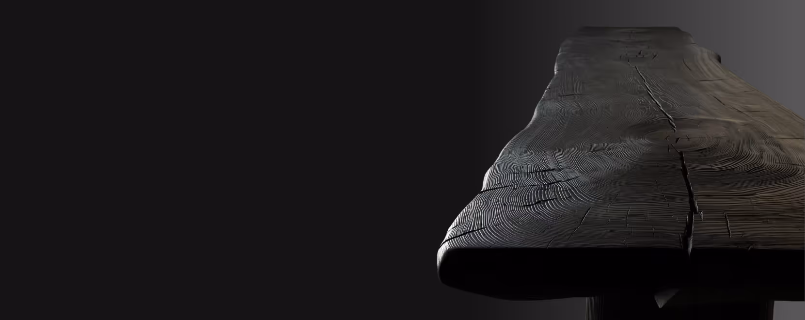 Close-up of a dark wooden table end with visible grain and cracks against a dark background.