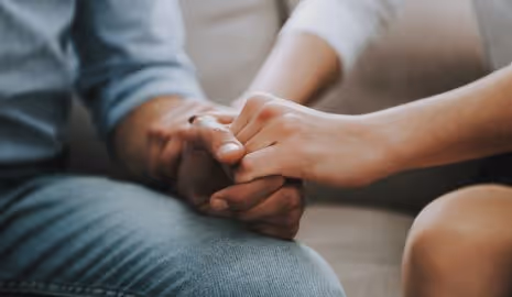 Man and woman holding hands while attending couples counseling.