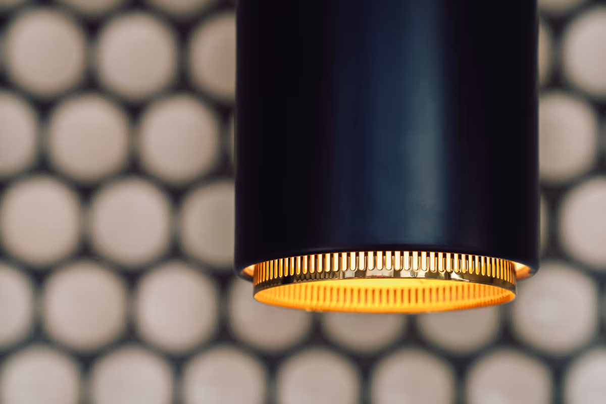 Close-up of a black pendant light against the ceramic disc wall at Maida Smiles
