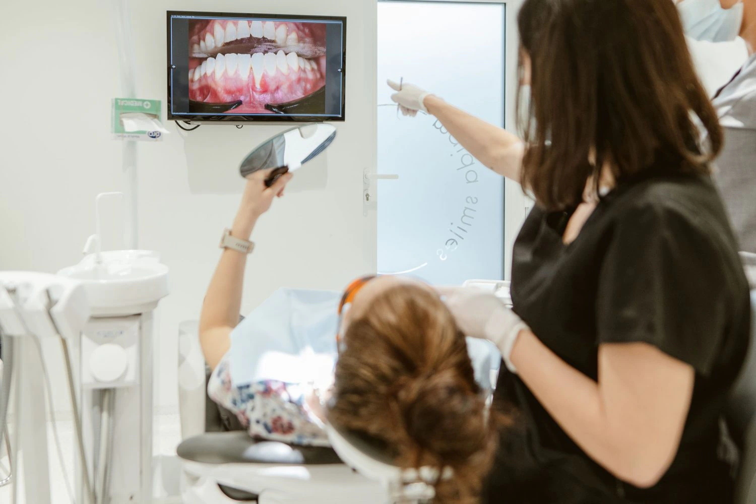 Dentist showing a patient an intraoral photo of their teeth and gums on a monitor during treatment