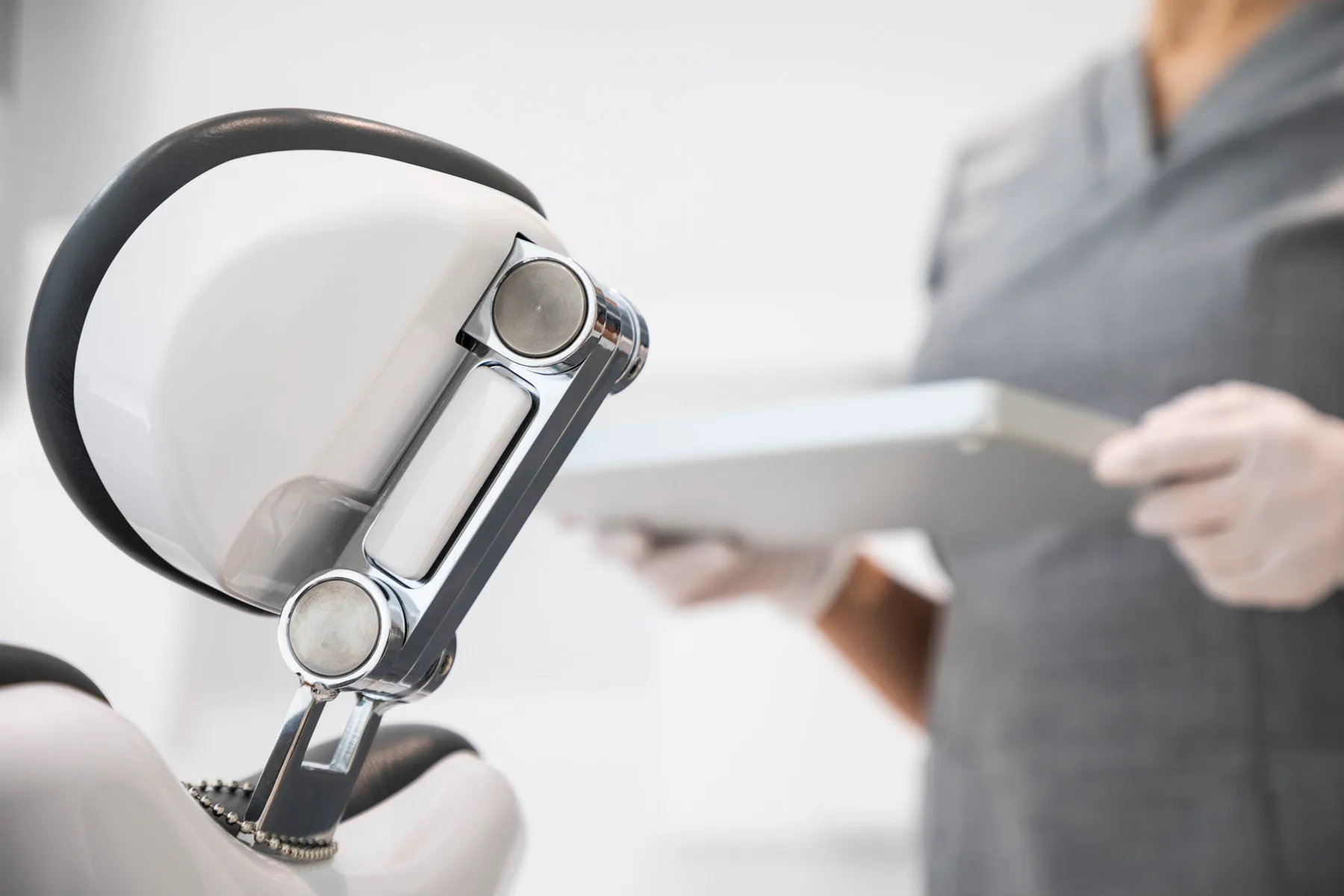 Dental chair headrest and instrument arm with a clinician preparing equipment at Maida Smiles dental clinic