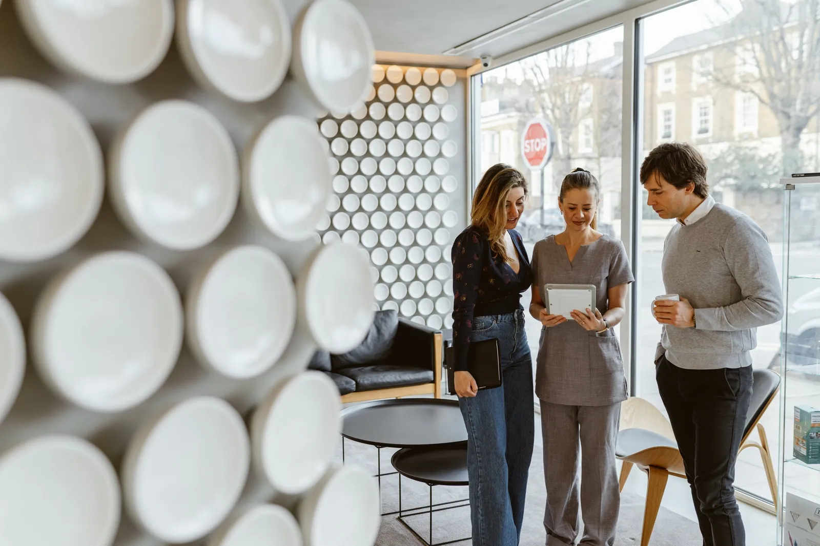 Dental clinic staff member writing on a clipboard while talking with two visitors