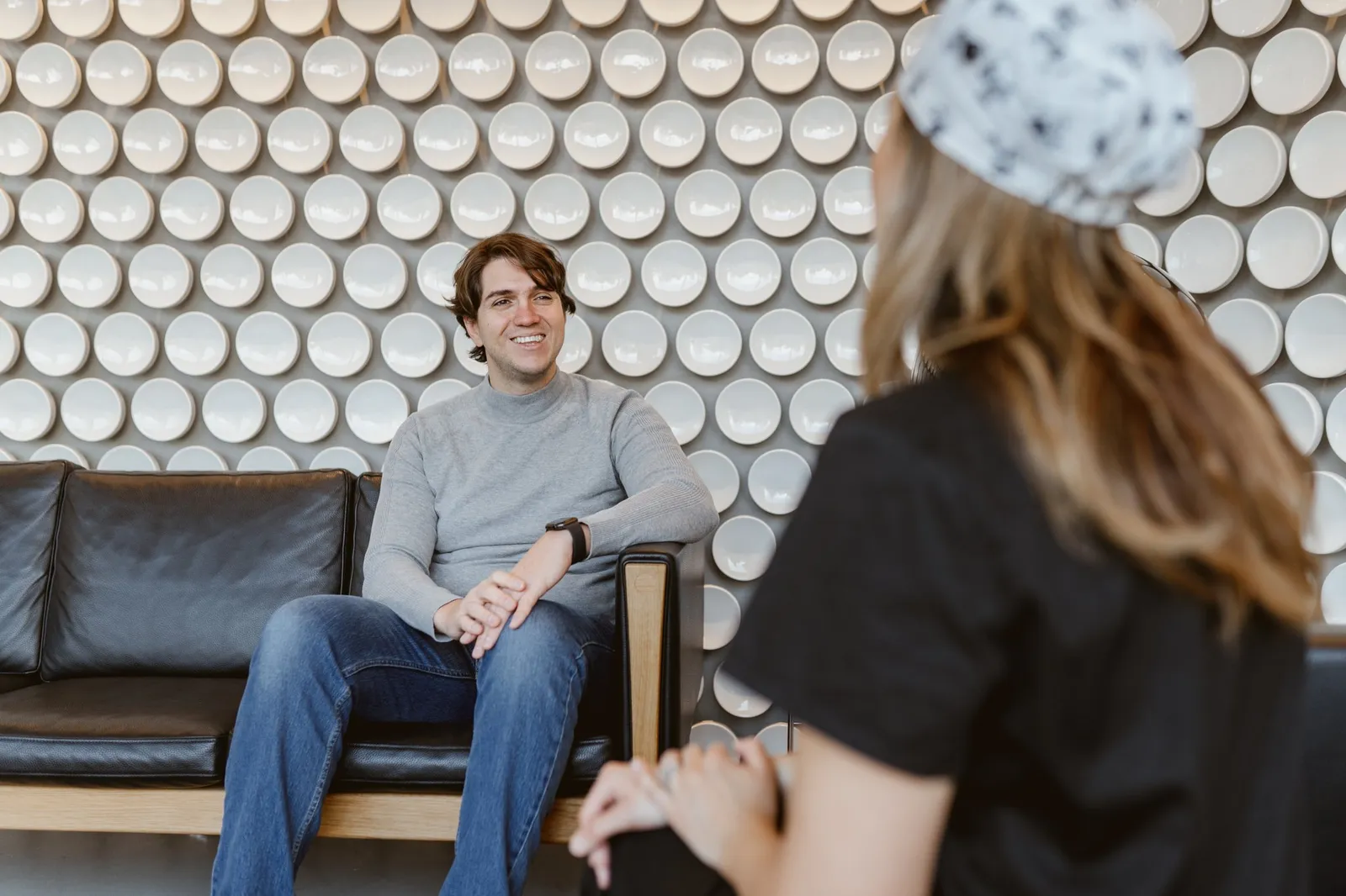 Smiling patient in conversation with a dental clinic team member in the waiting area.