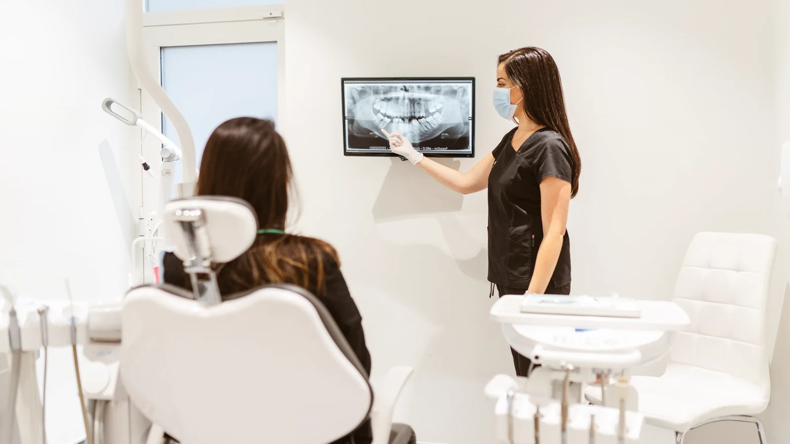 Dentist explaining a panoramic dental X-ray to a patient in a Maida Smiles treatment room.