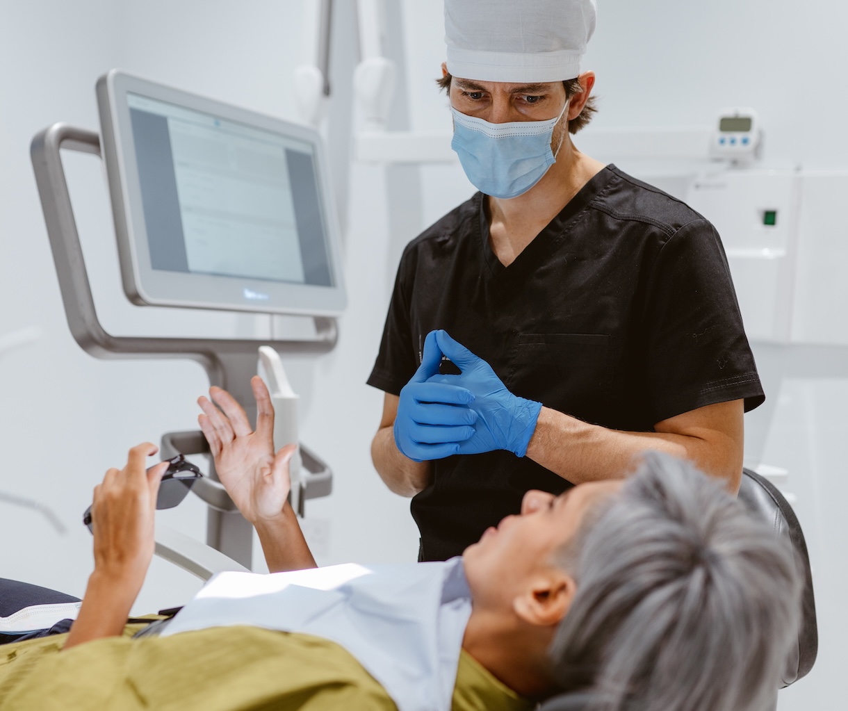 Dentist in a mask using a screen while treating a patient