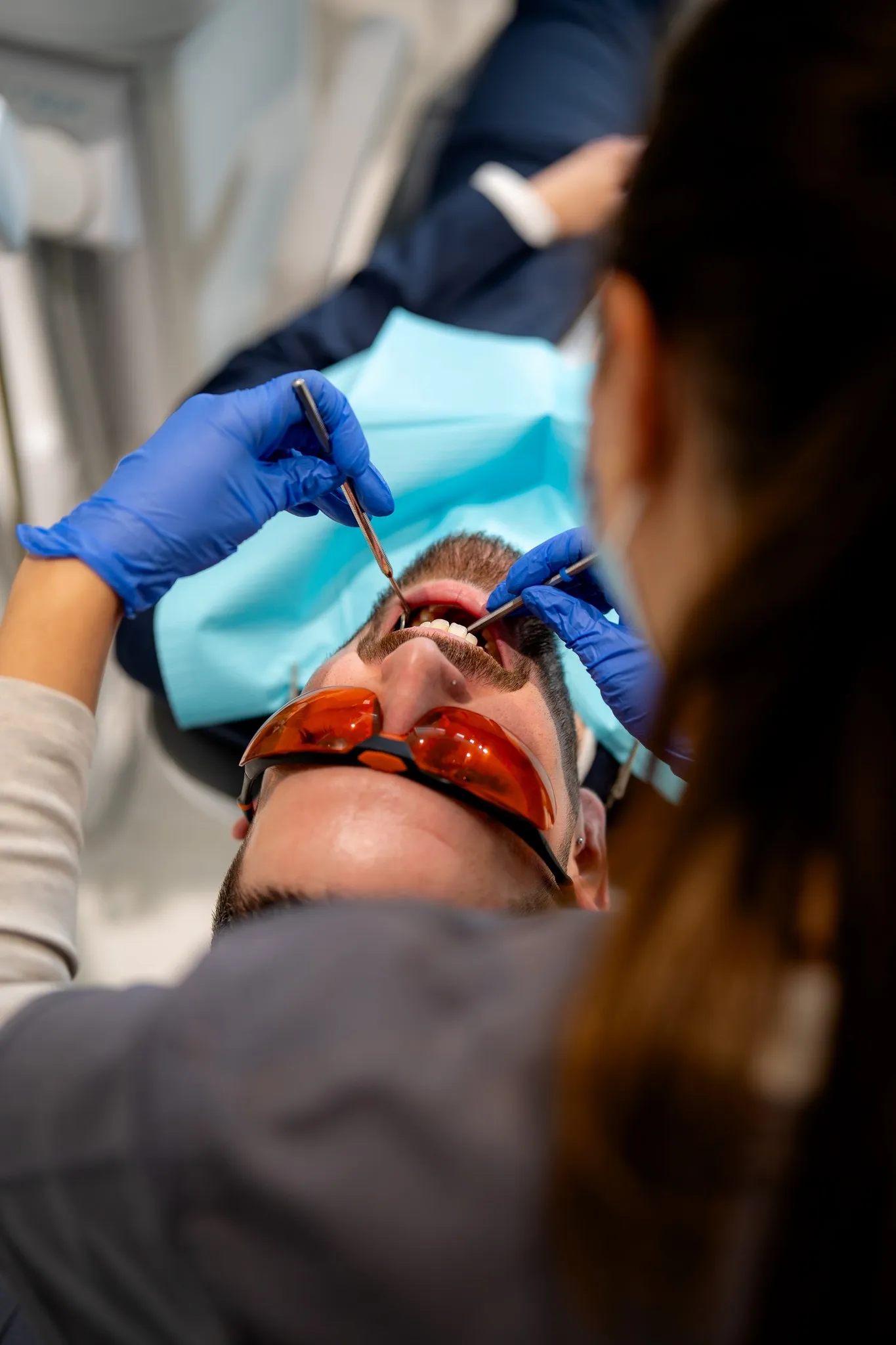 A clinician uses dental instruments to examine the mouth of a reclining adult.