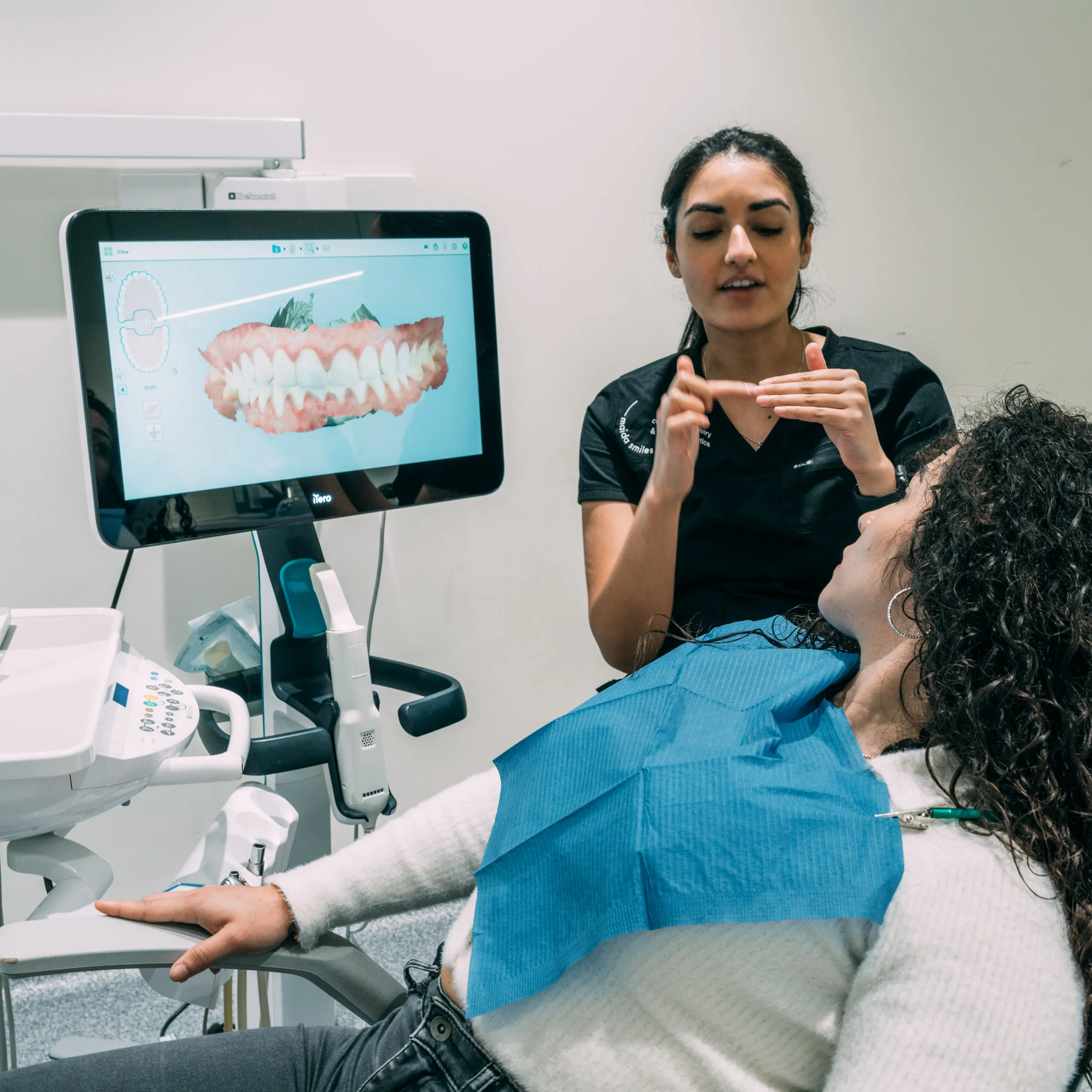Dentist explaining a digital 3D scan of teeth to a patient in the dental chair