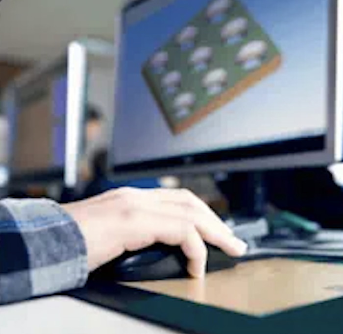 Person's hand using a stylus on a graphics tablet in front of a computer screen displaying 3D modeling software.