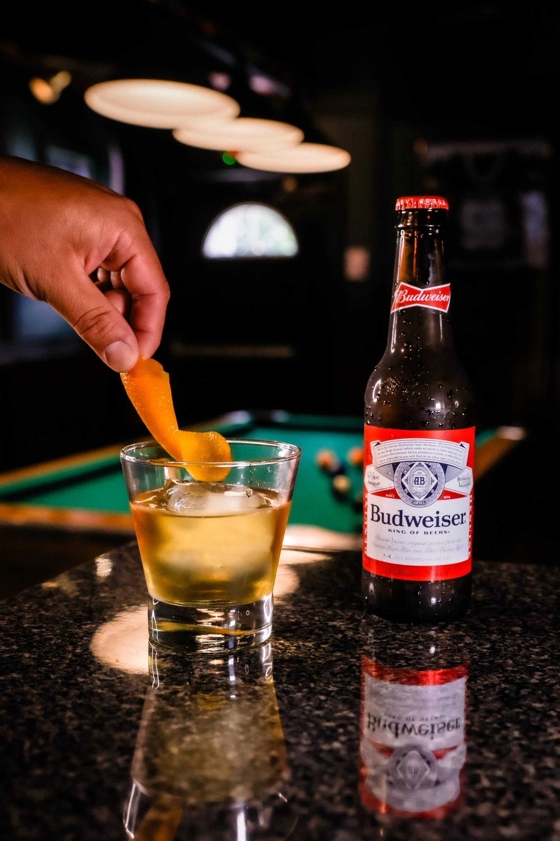 Glass of whiskey at Whiskey Reds Irish Pub next to a bottle of Budweiser in front of a pool table.