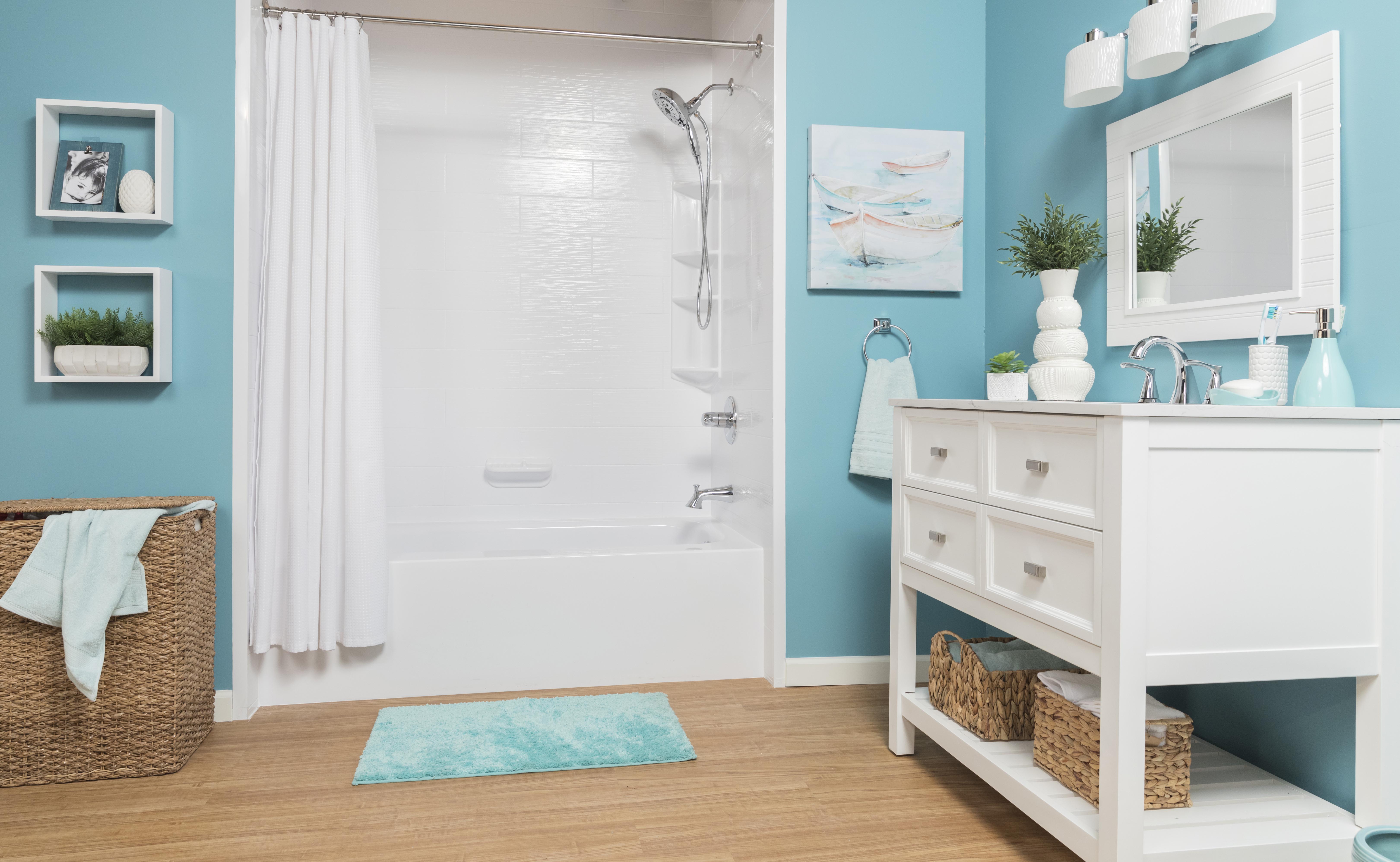 Bright and coastal-themed bathroom with turquoise blue walls, white vanity, and matching mirror. Features a white shower-tub combo with a curtain, wicker storage baskets, wood-look flooring, and beachy decor elements, creating a fresh, ocean-inspired space.