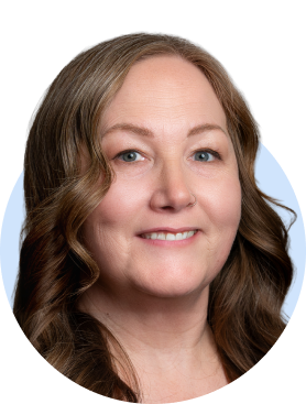 Smiling woman with wavy reddish-brown hair and black-rimmed glasses