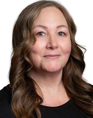 Smiling woman with wavy hair and glasses in professional headshot