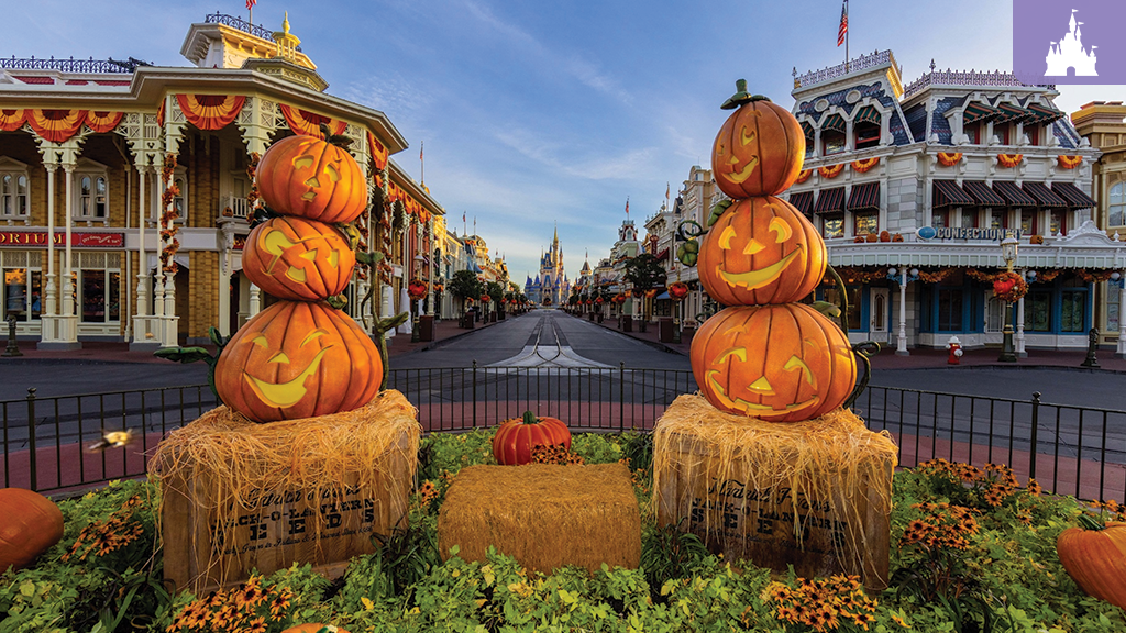 Stacked jack-o'-lanterns on hay bales line Main Street, U.S.A. at Magic Kingdom, with Cinderella Castle visible in the background during fall.