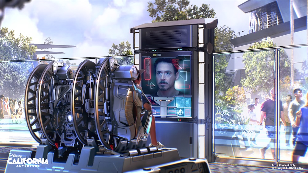 Visitor seated in a circular simulator pod facing a vertical screen showing a man’s face and digital interface, metal rings behind