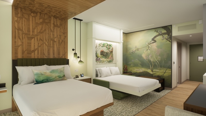 Hotel room with two white beds, green-accent headboards, hanging pendant lights and a forest mural on the wall.