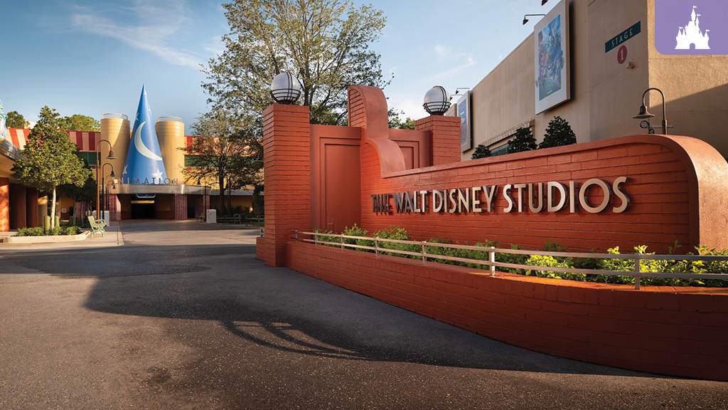 Brick entrance sign reading THE WALT DISNEY STUDIOS beside a courtyard featuring a blue Sorcerer’s Hat tower labeled ANIMATION.