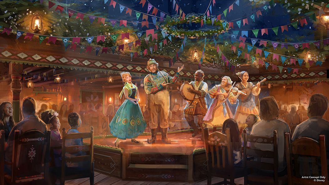 Folk dancers and musicians performing on a raised wooden stage under colorful pennant banners as seated families watch