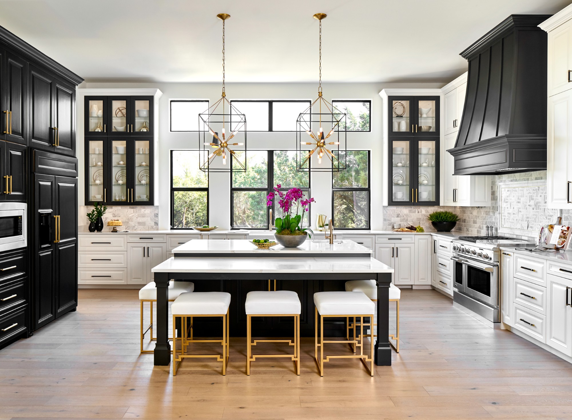 Elegant black and white kitchen with gold accents and large windows