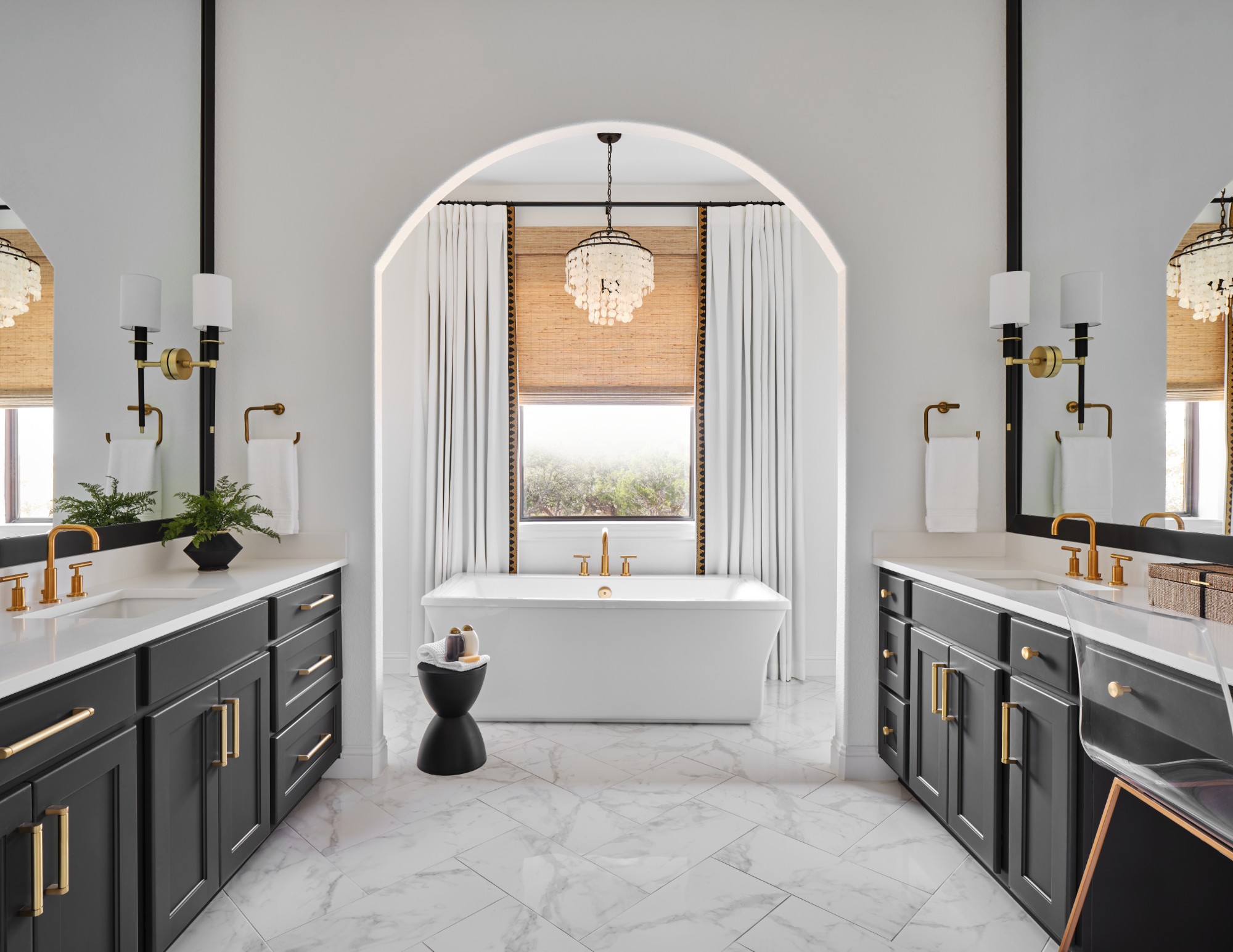 Luxurious bathroom with black cabinets, white tub, and gold fixtures