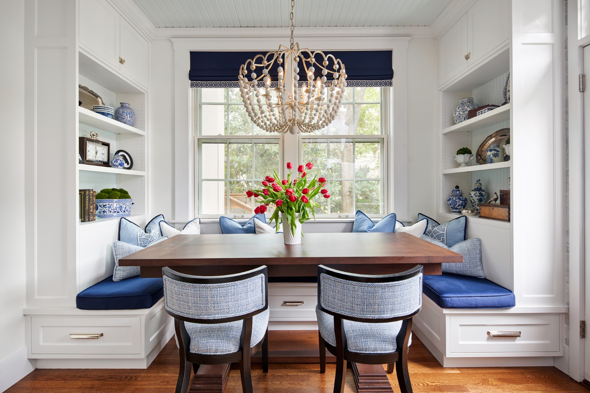 Elegant dining nook with built-in benches, beaded chandelier, and red tulips