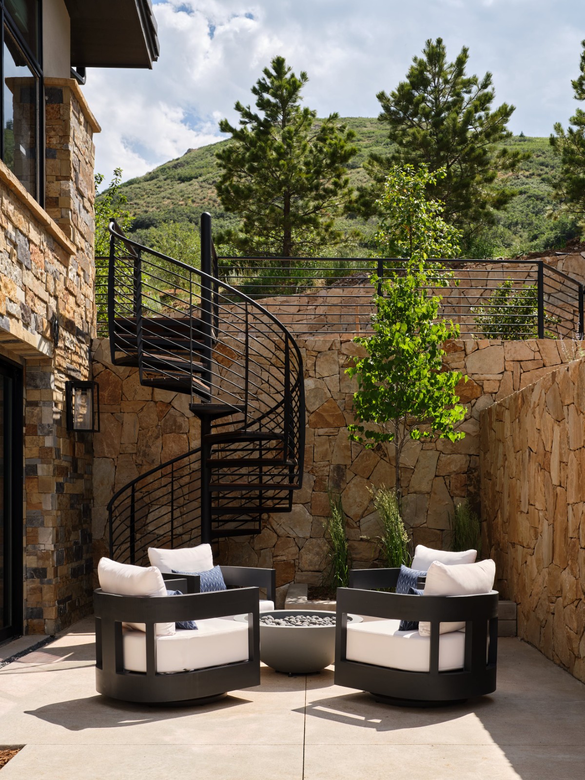 Outdoor patio with spiral staircase, stone walls, and modern chairs