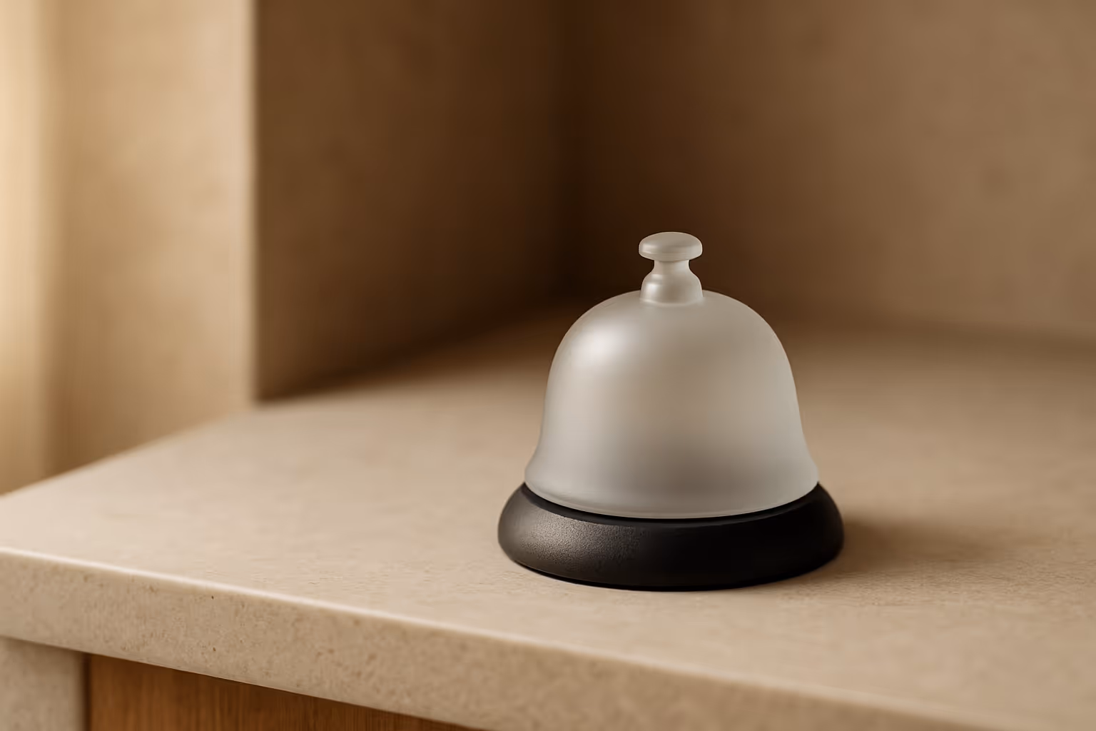 Minimal frosted glass reception bell on a light stone counter 