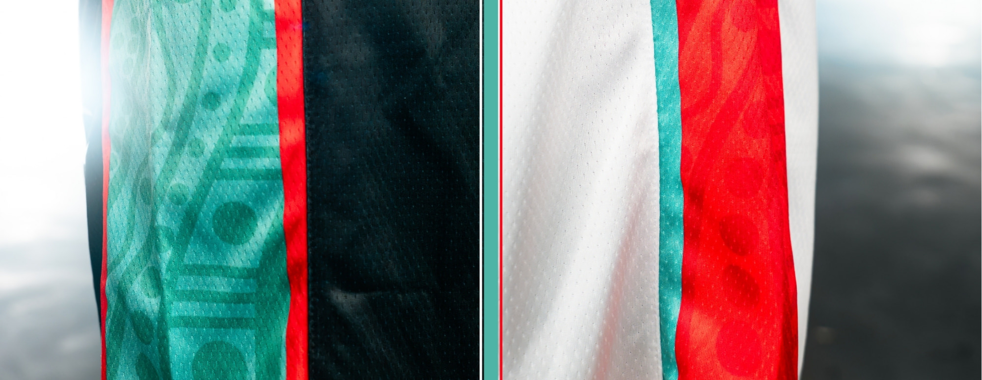 Home black and away white NBL27 jerseys side by side, showing the teal Indigenous-watermark side panel and red trim