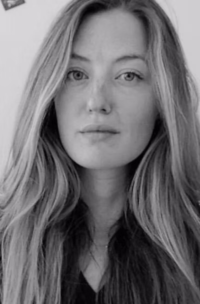 Black and white portrait of a woman with long wavy hair, looking directly at the camera.