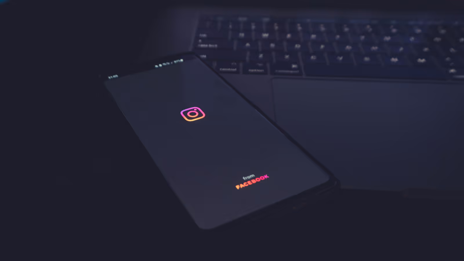 A smartphone open on Instagram is laid on top of an open laptop.