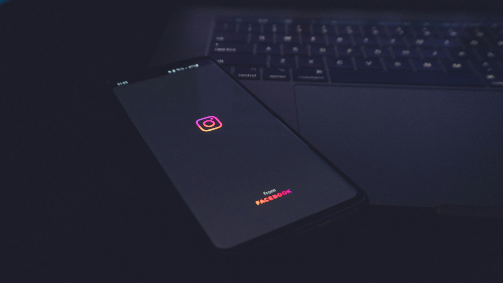 A smartphone open on Instagram is laid on top of an open laptop.