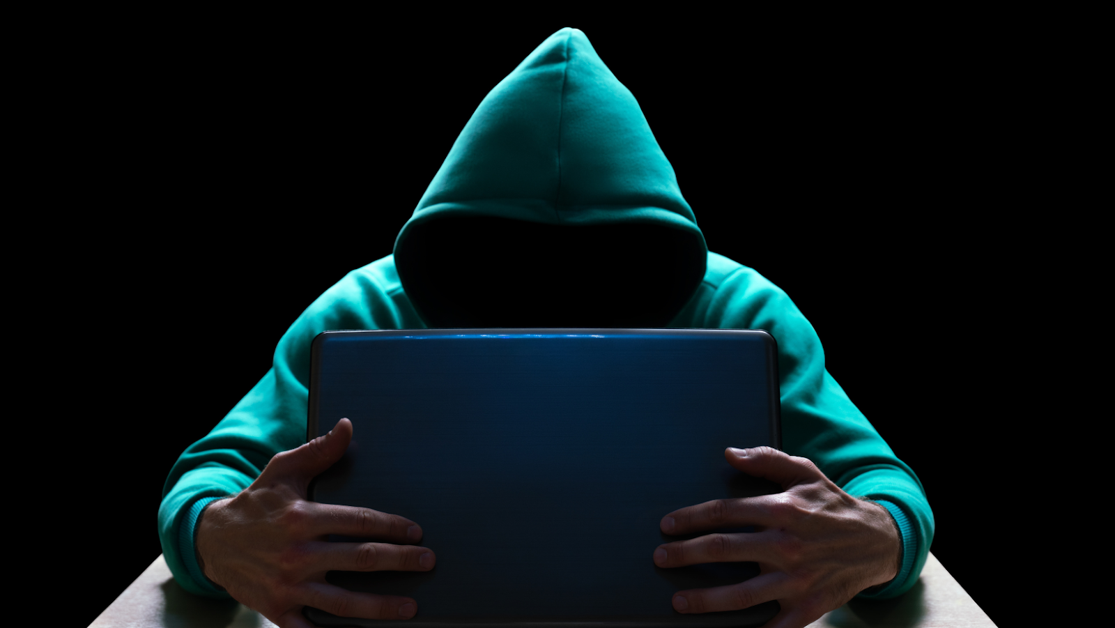 A scammer, represented by an anonymous person in a hoodie, hiding their identity, grips a laptop. Instagram scammers can access your account by sharing links on the web