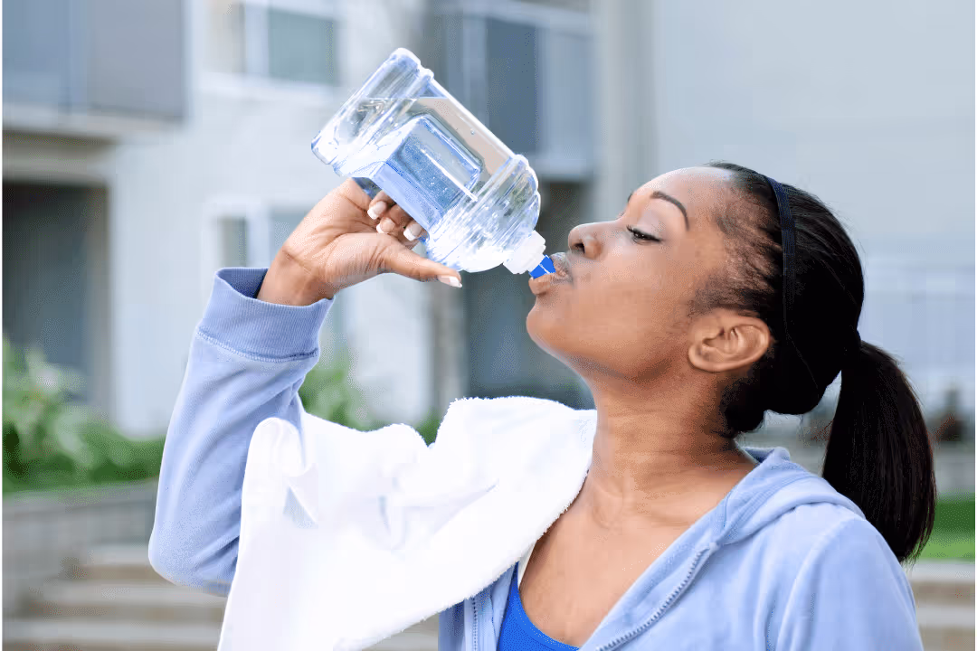woman drinking water out of water bottle during workout
